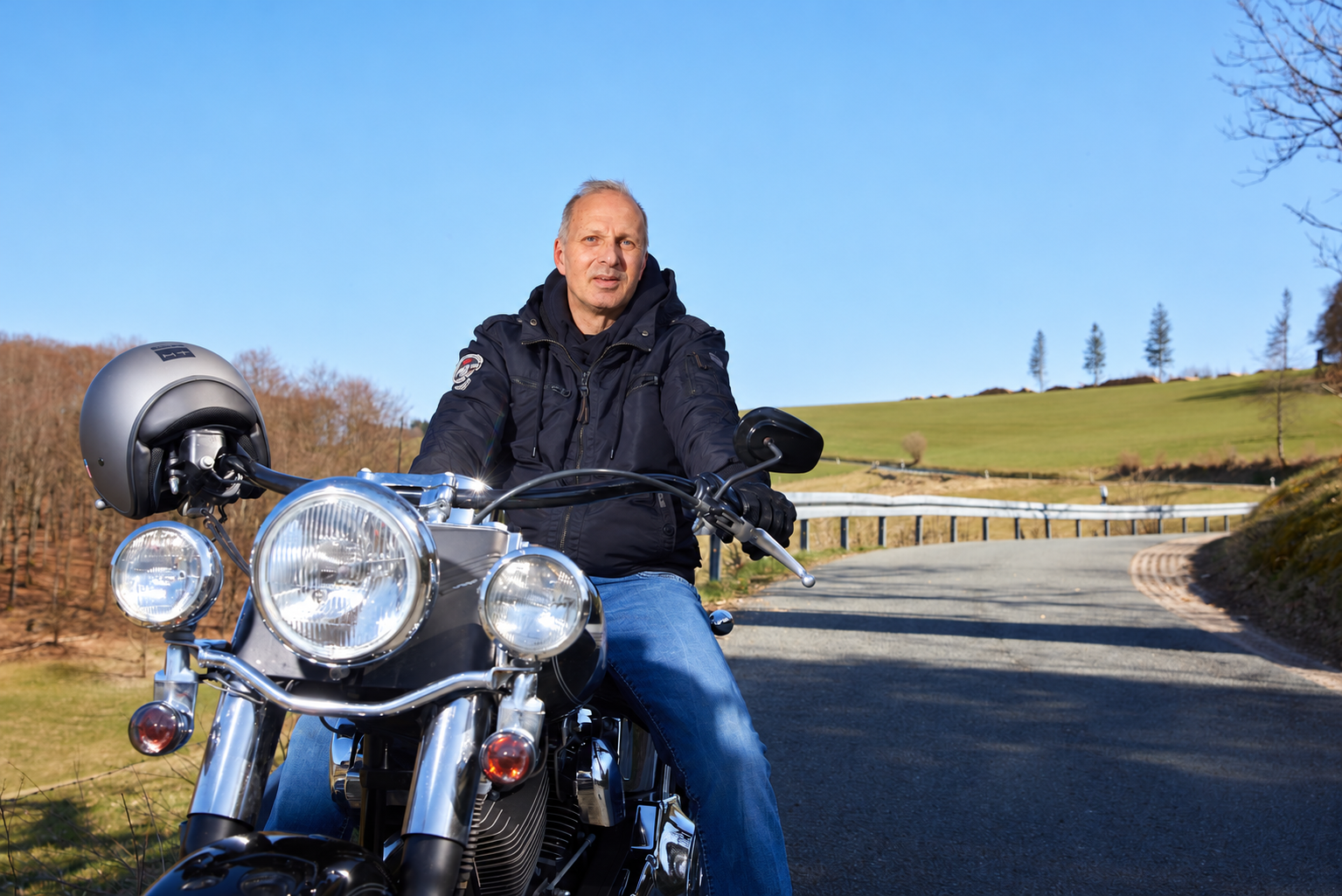 Ingo Kramer auf seinem Motorrad vor einer Landschaft mit kurviger Straße